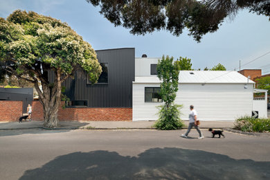 Inspiration for a mid-sized contemporary two-storey house exterior in Melbourne with wood siding and a metal roof.