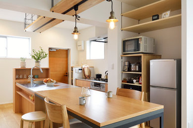This is an example of an asian galley eat-in kitchen in Tokyo with an integrated sink, flat-panel cabinets, medium wood cabinets, stainless steel benchtops, stainless steel appliances, light hardwood floors, with island, beige floor and grey benchtop.