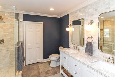 Large transitional master beige tile and stone tile porcelain tile and brown floor bathroom photo in Charlotte with shaker cabinets, white cabinets, a two-piece toilet, blue walls, an undermount sink, marble countertops and a hinged shower door