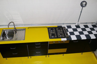 Foto de cocina lineal minimalista pequeña abierta con fregadero encastrado, armarios con paneles lisos, encimera de madera, electrodomésticos de acero inoxidable, suelo amarillo y encimeras multicolor