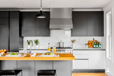 Medium sized contemporary single-wall kitchen/diner in Boston with a submerged sink, flat-panel cabinets, grey cabinets, engineered stone countertops, white splashback, marble splashback, integrated appliances, light hardwood flooring, an island, yellow floors and white worktops.