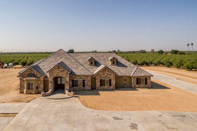 Large mountain style brown one-story stone gable roof photo in Other