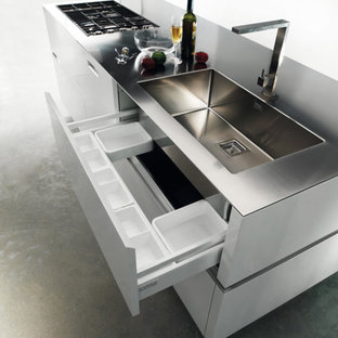 Выдающиеся фото от архитекторов и дизайнеров интерьера: маленькая параллельная кухня-гостиная в стиле модернизм с плоскими фасадами, техникой из нержавеющей стали, бетонным полом и островом