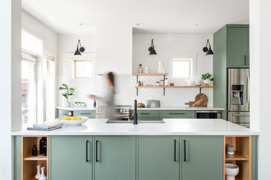 Inspiration for a mid-sized transitional galley medium tone wood floor, brown floor and vaulted ceiling eat-in kitchen remodel in Vancouver with an undermount sink, shaker cabinets, green cabinets, quartz countertops, white backsplash, ceramic backsplash, stainless steel appliances, an island and white countertops