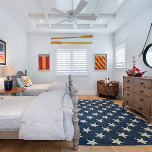 This is an example of a beach style kids' room for boys in Miami with light hardwood floors and white walls.