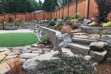 This is an example of a large transitional full sun backyard stone retaining wall landscape in Other.