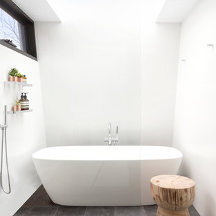 Imagen de cuarto de baño principal, minimalista, de tamaño medio, con bañera exenta, paredes blancas, suelo de baldosas de porcelana, ducha abierta, ducha a ras de suelo y suelo gris