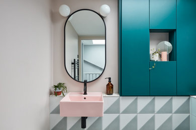 This is an example of a small scandinavian cloakroom in London with flat-panel cabinets, blue cabinets, a wall mounted toilet, multi-coloured tiles, ceramic tiles, pink walls, ceramic flooring, a wall-mounted sink, terrazzo worktops, multi-coloured floors, multi-coloured worktops, feature lighting and a built in vanity unit.