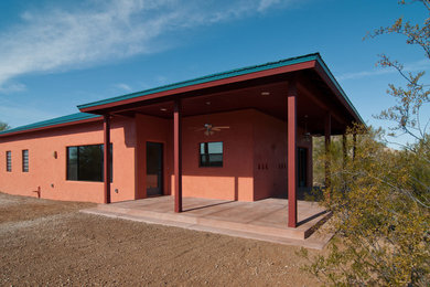 Mid-sized one-storey stucco brown house exterior in Phoenix with a hip roof and a metal roof.