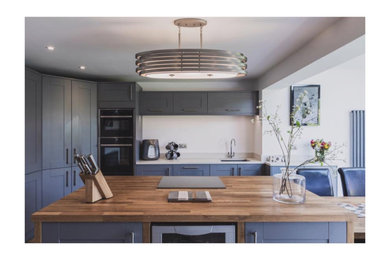 Design ideas for a medium sized contemporary u-shaped open plan kitchen in Essex with a submerged sink, recessed-panel cabinets, grey cabinets, composite countertops, white splashback, integrated appliances, ceramic flooring, an island, grey floors and beige worktops.