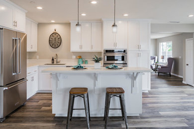 Example of a mid-sized trendy l-shaped medium tone wood floor and brown floor open concept kitchen design in San Luis Obispo with an undermount sink, shaker cabinets, white cabinets, quartz countertops, stainless steel appliances and an island