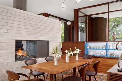 This is an example of a midcentury dining room in Austin with a two-sided fireplace.