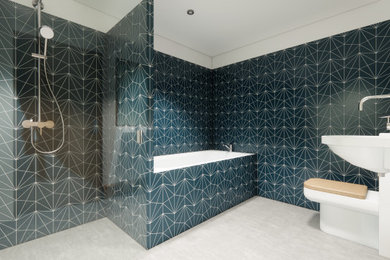 Ejemplo de cuarto de baño flotante escandinavo pequeño con bañera encastrada, ducha abierta, sanitario de una pieza, baldosas y/o azulejos azules, aseo y ducha, lavabo suspendido, suelo de cemento y suelo gris