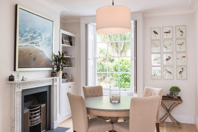 Inspiration for a transitional light wood floor dining room remodel in London with beige walls and a standard fireplace