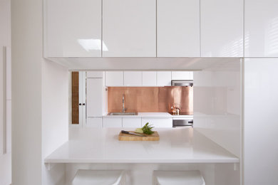 Mid-sized trendy galley eat-in kitchen photo in New York with flat-panel cabinets, white cabinets, quartz countertops, a peninsula and white countertops