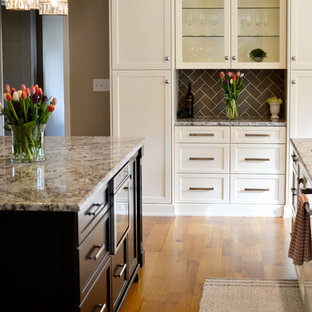 Bild på ett stort vintage linjärt skafferi, med en undermonterad diskho, luckor med infälld panel, vita skåp, granitbänkskiva, grått stänkskydd, stänkskydd i keramik, rostfria vitvaror, ljust trägolv och en köksö