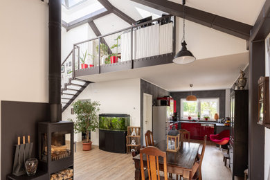 Großes, Repräsentatives, Offenes Modernes Wohnzimmer mit Vinylboden, Kaminofen, Kaminumrandung aus Metall, braunem Boden und freigelegten Dachbalken in Berlin