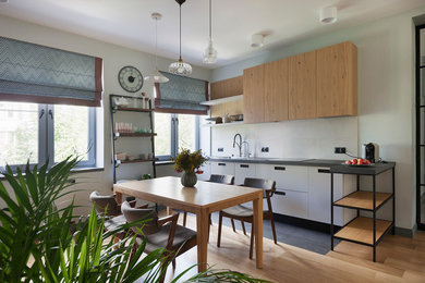 Photo of an industrial single-wall eat-in kitchen in Moscow with flat-panel cabinets, white cabinets, light hardwood floors, no island, beige floor and grey benchtop.