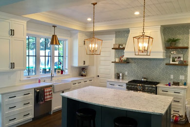 Inspiration for a mid-sized transitional dark wood floor and brown floor kitchen remodel in San Diego with a farmhouse sink, shaker cabinets, white cabinets, quartz countertops, white backsplash, subway tile backsplash, stainless steel appliances and an island