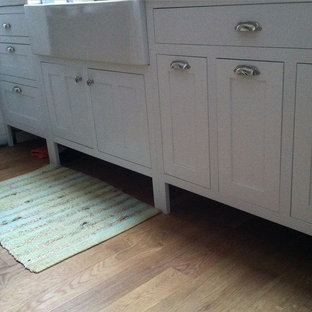 Small traditional kitchen pantry appliance - Kitchen pantry - small traditional galley medium tone wood floor kitchen pantry idea in Cedar Rapids with a farmhouse sink, recessed-panel cabinets, white cabinets, concrete countertops and stainless steel appliances