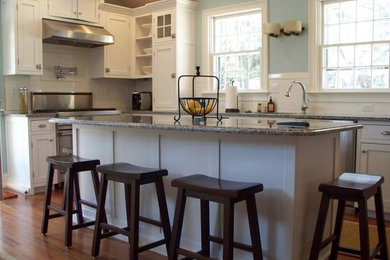 Inspiration for a mid-sized timeless l-shaped medium tone wood floor eat-in kitchen remodel in Boston with an undermount sink, beaded inset cabinets, white cabinets, granite countertops, white backsplash, subway tile backsplash, stainless steel appliances and an island