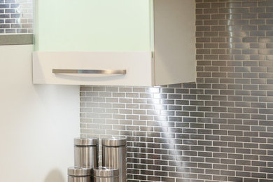 Inspiration for a mid-sized contemporary l-shaped porcelain tile kitchen remodel in Los Angeles with a double-bowl sink, white cabinets, quartz countertops, metallic backsplash, metal backsplash, stainless steel appliances and an island