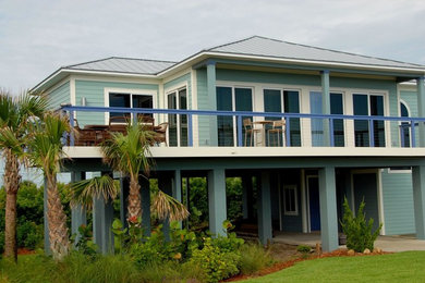 Photo of a large beach style two-storey blue house exterior in Orlando with wood siding, a hip roof and a metal roof.