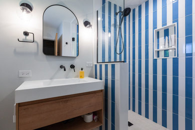 Mid-sized mid-century modern master blue tile single-sink alcove shower photo in Chicago with flat-panel cabinets, brown cabinets, a hinged shower door and a floating vanity