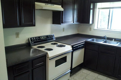 Inspiration for a mid-sized timeless ceramic tile and beige floor enclosed kitchen remodel in Albuquerque with a double-bowl sink, recessed-panel cabinets, black cabinets, laminate countertops, white appliances and no island