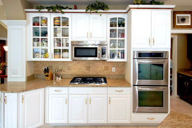 Large elegant ceramic tile eat-in kitchen photo in Other with white cabinets, beige backsplash, stainless steel appliances, an island, raised-panel cabinets, mosaic tile backsplash and an undermount sink