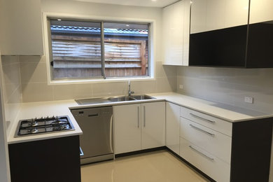 This is an example of a small contemporary u-shaped eat-in kitchen in Melbourne with a double-bowl sink, white cabinets, quartz benchtops, grey splashback, ceramic splashback, stainless steel appliances, ceramic floors and no island.