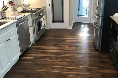 Inspiration for a mid-sized transitional galley open plan kitchen in Toronto with medium hardwood floors, brown floor, a peninsula, raised-panel cabinets, white cabinets, quartzite benchtops, an undermount sink, white splashback and stainless steel appliances.