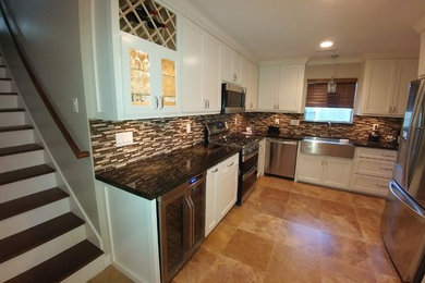 Example of a mid-sized arts and crafts u-shaped ceramic tile enclosed kitchen design in Houston with a farmhouse sink, shaker cabinets, white cabinets, granite countertops, multicolored backsplash, matchstick tile backsplash, stainless steel appliances and no island