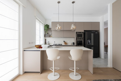 Idee per una grande e bianca e tortora cucina minimalista con lavello sottopiano, ante lisce, ante beige, top in superficie solida, paraspruzzi bianco, paraspruzzi in quarzo composito, elettrodomestici neri, parquet chiaro, penisola, pavimento beige e top bianco
