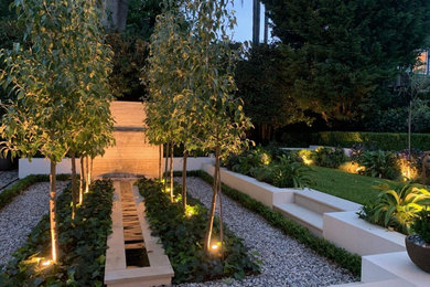 Idee per un giardino formale tradizionale esposto a mezz'ombra di medie dimensioni e dietro casa con una cascata e ghiaia