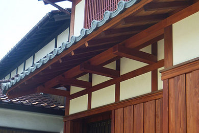 Ejemplo de fachada asiática de dos plantas con tejado a dos aguas y tejado de teja de barro
