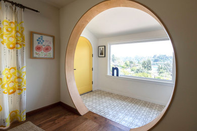 ロサンゼルスにある高級な広いエクレクティックスタイルのおしゃれな玄関ロビー (白い壁、コンクリートの床、黄色いドア、ベージュの床、三角天井) の写真