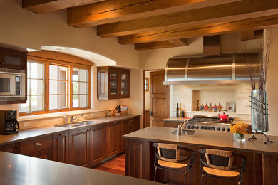 Photo of a large u-shaped eat-in kitchen in Albuquerque with an undermount sink, raised-panel cabinets, medium wood cabinets, beige splashback, stainless steel appliances, medium hardwood floors, with island, quartz benchtops, subway tile splashback, brown floor, grey benchtop and exposed beam.
