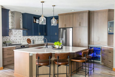 Example of a mid-sized transitional l-shaped eat-in kitchen design in Other with a single-bowl sink, flat-panel cabinets, light wood cabinets, quartz countertops, white backsplash, ceramic backsplash, stainless steel appliances, an island and white countertops