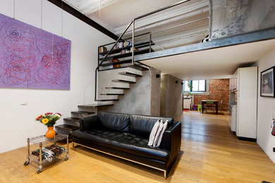 Esempio di un ampio soggiorno minimal stile loft con pareti bianche, parquet chiaro e pavimento marrone