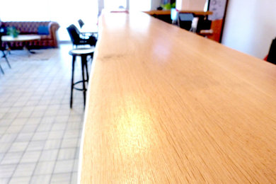 Aménagement d'un grand bar de salon campagne en U avec des tabourets et un plan de travail en bois.