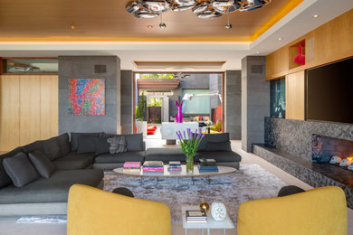 Example of a large open concept beige floor and wood ceiling living room design in San Diego with a stone fireplace and a media wall