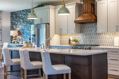 This is an example of a large rural kitchen in Baltimore with a submerged sink, shaker cabinets, white cabinets, engineered stone countertops, grey splashback, cement tile splashback, stainless steel appliances, medium hardwood flooring, an island, brown floors and white worktops.