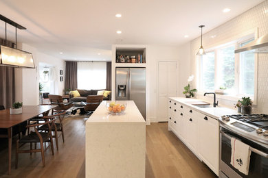 Minimalist medium tone wood floor and brown floor eat-in kitchen photo in New York with an undermount sink, white cabinets, quartz countertops, yellow backsplash, ceramic backsplash, stainless steel appliances and an island