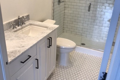 Photo of a medium sized contemporary shower room bathroom in Denver with raised-panel cabinets, white cabinets, an alcove shower, a two-piece toilet, white tiles, porcelain tiles, grey walls, porcelain flooring, a submerged sink, quartz worktops, white floors, a hinged door and white worktops.