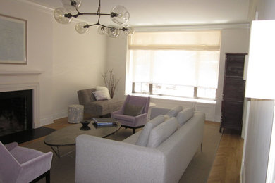 Mid-sized mid-century modern enclosed medium tone wood floor living room photo in New York with white walls, a standard fireplace, a wood fireplace surround and no tv
