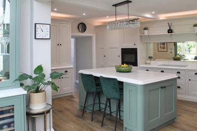 Example of a large classic eat-in kitchen design in Other with a drop-in sink, shaker cabinets, green cabinets, quartzite countertops, white backsplash, quartz backsplash, black appliances, an island and white countertops