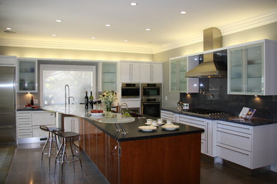 Kitchen - mid-sized contemporary l-shaped porcelain tile and gray floor kitchen idea in San Francisco with flat-panel cabinets, white cabinets, quartz countertops, gray backsplash, stone slab backsplash, stainless steel appliances and an island
