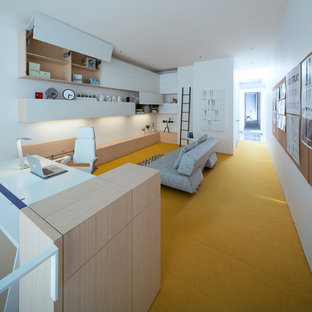 Large modern study in Vancouver with white walls, carpet, no fireplace, a built-in desk and yellow floors.