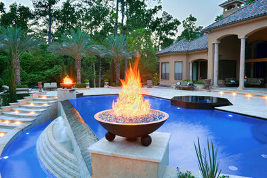 This is an example of a large mediterranean backyard custom-shaped pool in Houston with natural stone pavers.